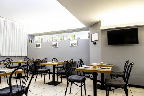 a dining room with tables and chairs and a flat screen tv at Hotel Berlino in Milan