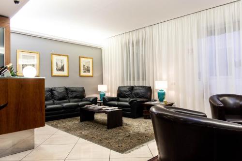 ミラノにあるホテル ベルリノのリビングルーム(黒革の家具、カーテン付)