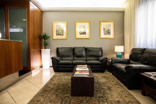 a living room with black leather couches and a coffee table at Hotel Berlino in Milan