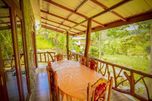 eine Veranda mit einem Tisch und Stühlen auf dem Balkon in der Unterkunft Blue Heaven Cottage in Ella
