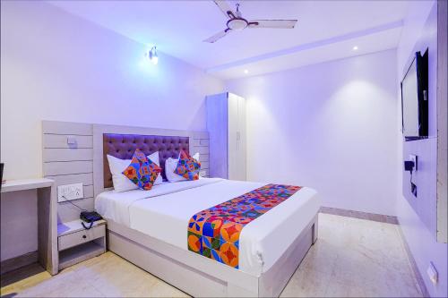 a white bedroom with a large bed with colorful pillows at FabExpress Embassy Suites in Mumbai