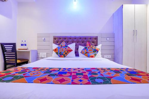 FabExpress Embassy Suites في مومباي: غرفة نوم مع سرير ولحاف ملون