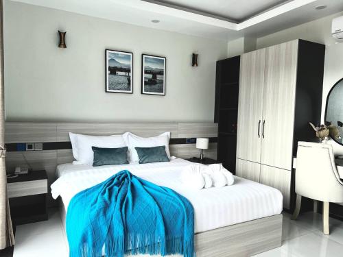a bedroom with a large bed with a blue blanket on it at Twin Hotel Kampot in Kampot