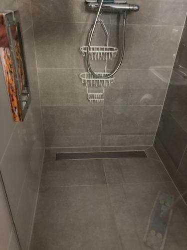 een douche met een douchekop in de badkamer bij Luxe prive-kamer - studio in villa aan zee, Dishoek, vernieuwd in Dishoek