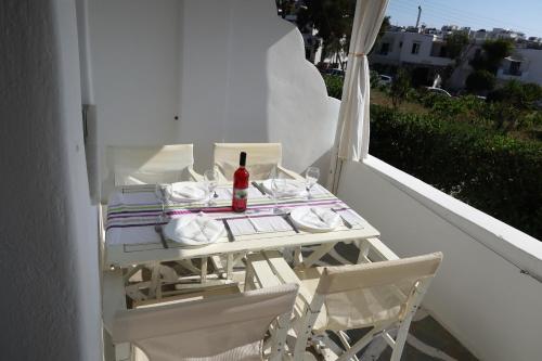 una mesa blanca con una botella de vino en el balcón en Afroditi studios, en Kampos