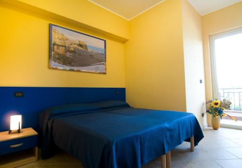 1 dormitorio con cama azul y pared amarilla en B&B Mare Nostrum, en Catona