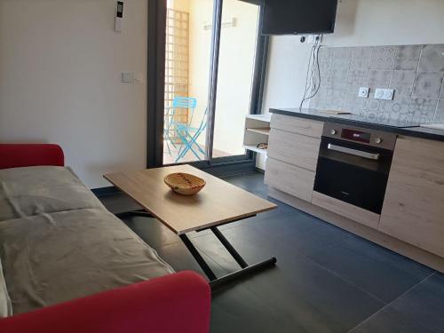 een woonkamer met een tafel en een bank en een keuken bij Le Rubis in Gruissan