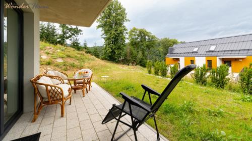 a patio with chairs and a table and a building at Wonder Home Myśliwska - Domki przy stoku Karpatka - na terenie kompleksu plac zabaw, zewnętrzna siłownia i sklep in Karpacz