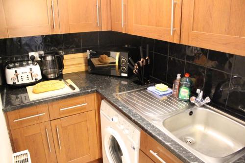 a kitchen counter with a sink and a dishwasher at Flat 1, Westhill in Leeds