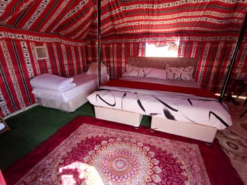 a room with two beds and a rug in a yurt at Hamood desert local camp in Al Wāşil