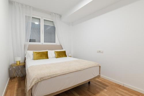 Dormitorio blanco con cama con almohadas amarillas en Casco antiguo2 Piscina y Parking by Vero, en Altea