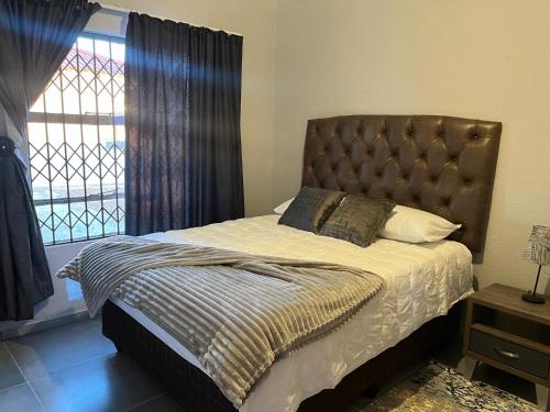 a bedroom with a bed with a large window at Mafikeng Boutique Lodge in Mahikeng