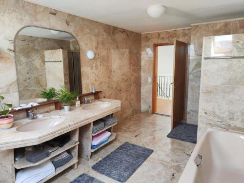 a bathroom with two sinks and a tub and a mirror at Richie's Landhaus im Allgäu in Pfaffenhausen