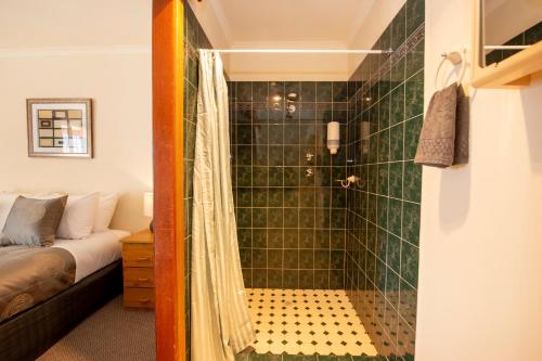 a bathroom with a shower with green tiles at Ardrossan Hotel Motel in Ardrossan