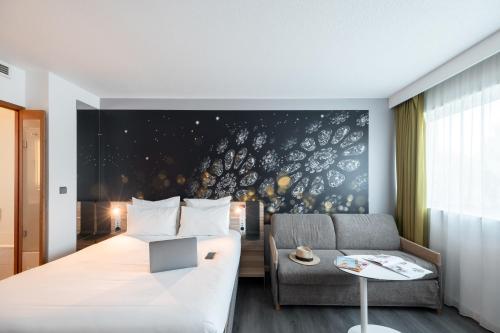 a hotel room with a bed and a couch at Novotel Chartres in Chartres