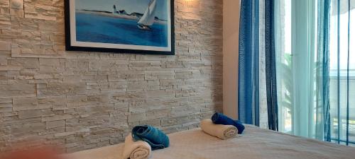 een slaapkamer met een stenen muur en een bed met handdoeken bij Sea view Perea Apartment in Perea