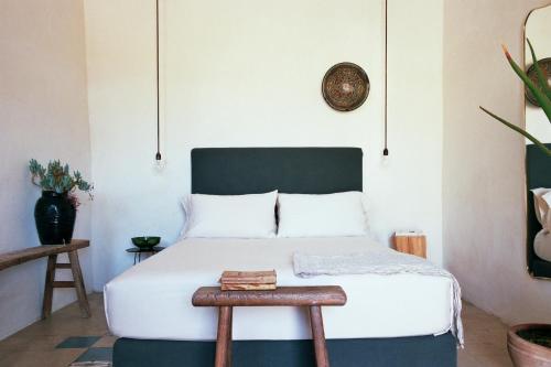 a bedroom with a white bed with a wooden stool at Dimora delle Balze in Noto