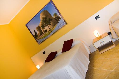 een slaapkamer met een bed met witte lakens en gele muren bij B&B Mare Nostrum in Catona