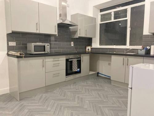 a kitchen with white cabinets and a microwave at Central Bridgewater Flat in Bridgwater
