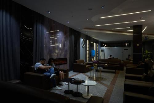 two people sitting in a living room with a fireplace at MyHotel Erbil in Erbil