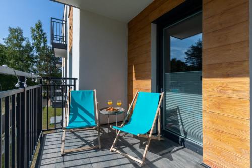 two chairs and a table on a balcony at Apartments with Parking - Klimaty Baltyku by Renters in Dziwnów