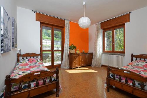 Duas camas num quarto com paredes e janelas cor-de-laranja em Casa Virginia em Mandello del Lario