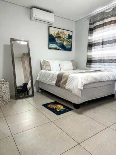 a bedroom with a large bed and a mirror at The Abode in Gaborone