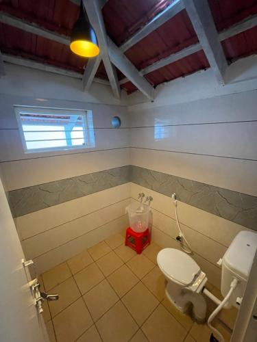 a bathroom with a toilet and a red box at The Estate HomeStay in Attigundi