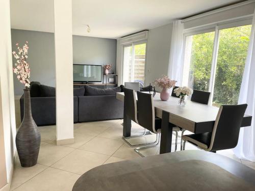 een woonkamer met een tafel en een bank bij Agréable et grande maison avec parking + jardin in Villeurbanne