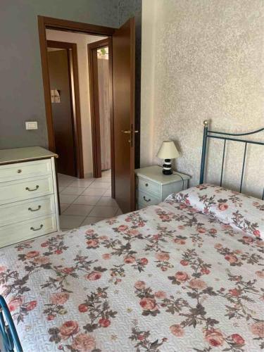 a bedroom with a bed with a floral bedspread and a dresser at IL SENSO DI LIBERTA' in Rieti