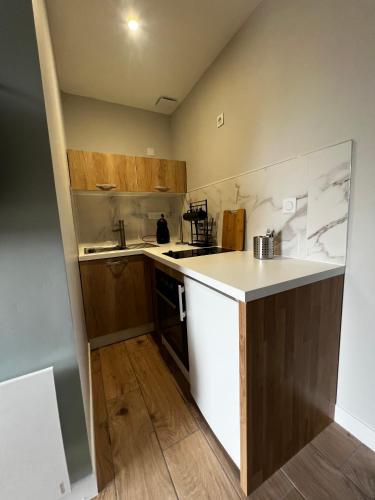 a small kitchen with a white counter and wooden cabinets at Scorfel Lodge, Studio 52, GR34, terrasse & calme in Trégastel