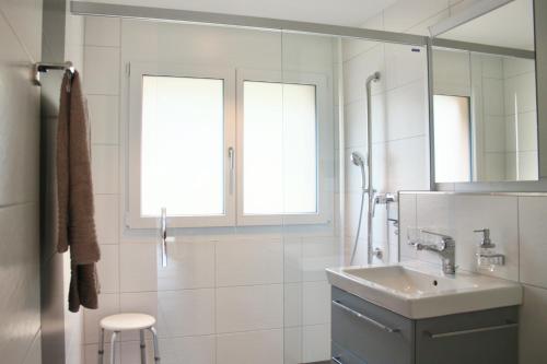 a white bathroom with a sink and a shower at Apartment Arvenwald in Kandersteg