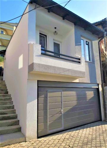 a white house with a garage door and stairs at Studio Apartment - Prizren in Prizren