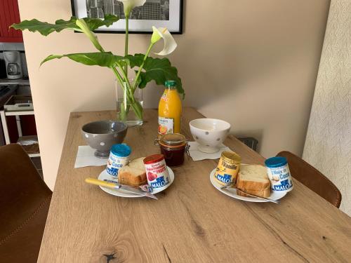 a table with two plates of sandwiches and a bottle of orange juice at STUDIO 3 Mn de la PLAGE Terrasse Vélos Proche de la ville fortifiée in Saint Malo