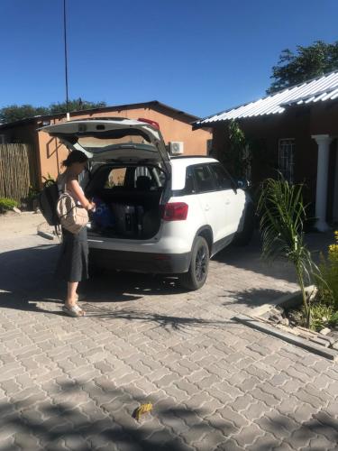 una mujer de pie junto a un coche con el baúl abierto en Jayla Apartment en Maun