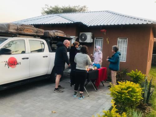 a group of people standing around a table next to a van at Jayla Apartment in Maun