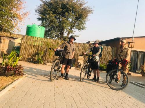 Drei Männer stehen mit ihren Fahrrädern auf einer Straße in der Unterkunft Jayla Apartment in Maun