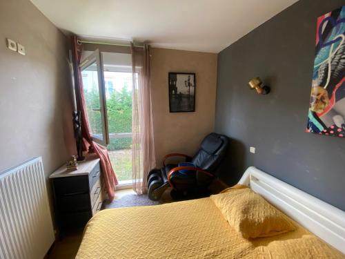 1 dormitorio con 1 cama, 1 silla y 1 ventana en Agréables chambres dans maison suspendue, en Saint-Étienne