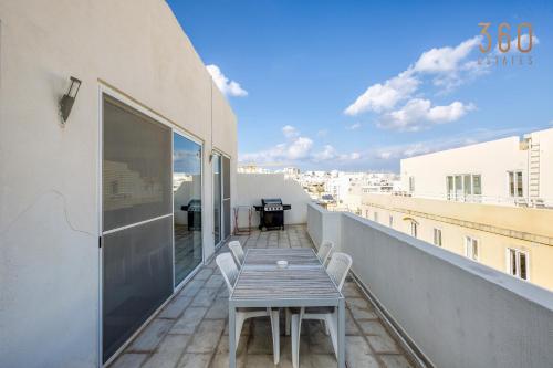 - un balcon avec une table et des chaises dans un bâtiment dans l'établissement Lovely penthouse with private BBQ & WIFI in GZIRA BY 360 Estates, à Il-Gżira