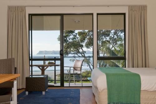 ein Hotelzimmer mit einem Bett und Meerblick in der Unterkunft Beachfront Resort in Whitianga