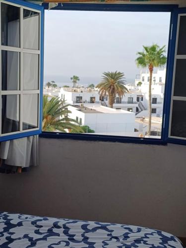 1 dormitorio con ventana y vistas a la ciudad en T2 RESIDENCE ATALAYA PUERTO DEL CARMEN LANZAROTE, en Puerto del Carmen