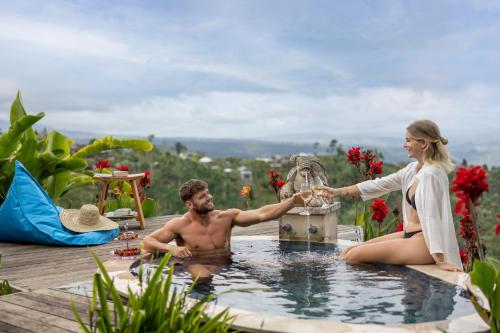 a man and a woman are shaking hands in a hot tub at Munduk Tentrem Resort in Munduk