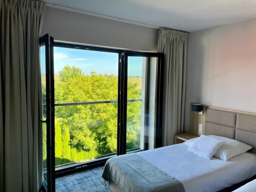 a bedroom with a bed and a large window at Gościniec "Nad Wartą" in Uniejow