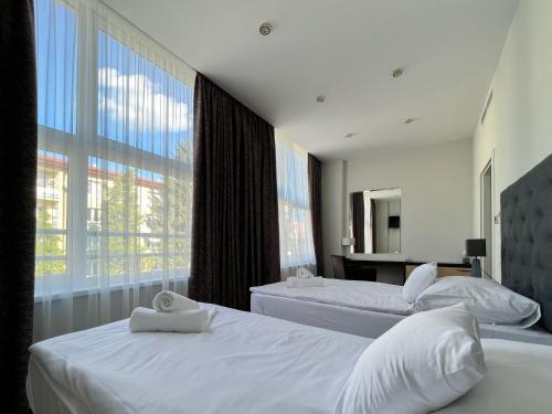 1 dormitorio con 2 camas y ventana grande en AM HOTEL WELLNESS ****, en Rimavská Sobota