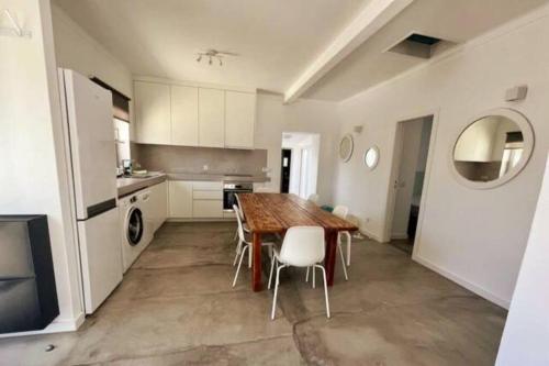 a kitchen with a wooden table and white cabinets at New Beach House near main street close PraiaGrande in Colares