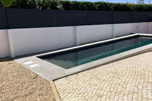 a swimming pool sitting next to a white fence at New Beach House near main street close PraiaGrande in Colares