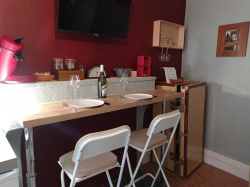 a bar with two chairs and a table with wine glasses at Appartement le bar du JURA in Saint-Claude