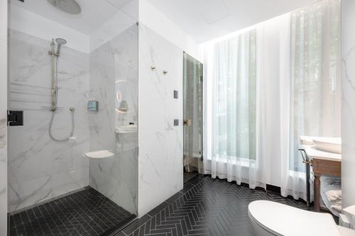 a bathroom with a shower and a toilet and a sink at Movenpick Hotel Tallinn in Tallinn