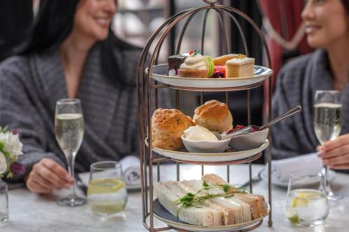 a woman sitting at a table with a plate of food at Oulton Hall Hotel, Spa & Golf Resort in Leeds