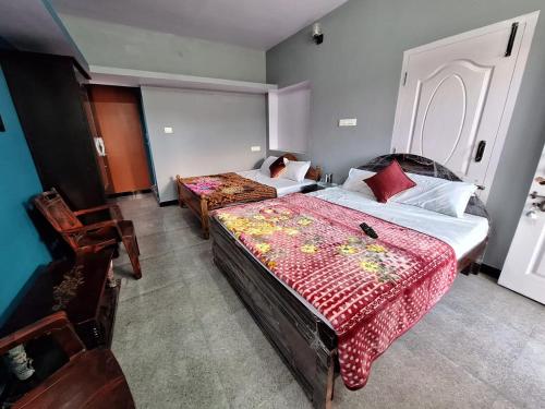 une chambre avec deux lits et deux chaises dans l'établissement Golden View Cottage Ooty, à Ooty
